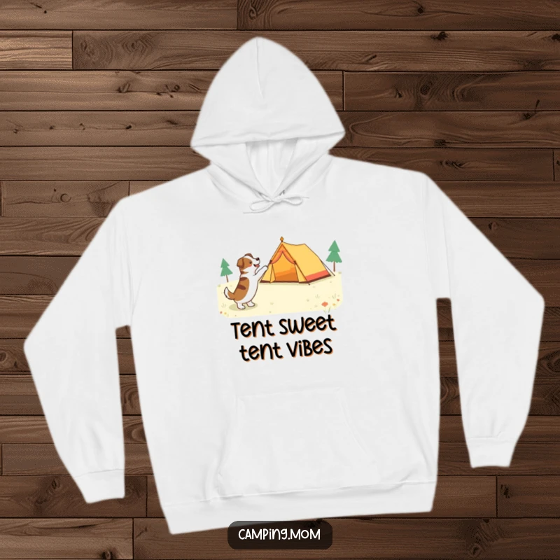 Funny dog pointing with pure excitement at a brightly colored tent in a forest clearing, on a warm hoodie.